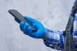 © vadish - Close-up of a construction worker handyman in protective gloves and workwear using a modern smartphone. Concept digital technology into manual labor and job.