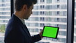 © stockbusters - Employee browsing chroma key tablet reading email standing office window closeup