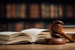 © Andy - A wooden gavel rests beside an open book on a table, symbolizing justice, law, and the legal system with a blurred background of books.