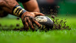 © thanakrit - Close-Up of Rugby Player's Hand Grasping Muddy Ball on Grass During Intense Game Action