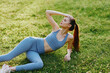 © SHOTPRIME STUDIO - Active young woman in sportswear lounging on grass, showcasing a healthy lifestyle, fitness, and mindfulness in a vibrant green outdoor setting