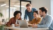 © Big - Group of colleagues collaborating around a laptop in a modern office setting