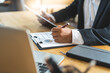 © Pormezz - Close up view hands of businessman using calculator and doing accounting with graph and documents on the table.