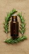 © giandra - Amber bottle of essential oil surrounded by rosemary sprigs on a beige background