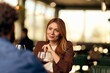 © bnenin - Young Woman in a Blazer Engaged in a Conversation Over Wine in a Cafe