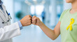 © CURIOUS TALENTS - Doctor and Patient Fist Bump Celebrating Success with Ribbon
