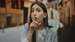 © Krakenimages.com - Hispanic woman in blue striped shirt presses finger to lips for silence on historic street at dusk; quiet secrecy.