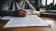 © Katerina - Technical writer reviewing and editing printed manual at home office desk with focused concentration