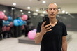 © Ranta Images - Hispanic bald man athlete in gym using mobile phone while texting in classroom