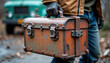 © Angavlan - Worker carrying toolbox with rusty tool case, construction worker holding vintage box in outdoor setting, showcases worn equipment.