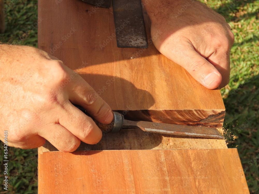 Foto de Stock Man hands using a chisel to make cut in a wood plank ...