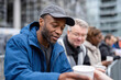 © Milos - A man joyfully receives a warm cup from a volunteer, depicting generosity and community spirit, emphasizing the beauty of human kindness in everyday acts.