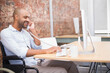 © wavebreak3 - Man in wheelchair holding telephone while typing on keyboard in office, copy space