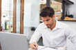 © WavebreakMediaMicro - Man writing in notebook at café table beside laptop computer and coffee cup, copy space