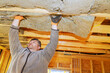 © ungvar - Construction worker lifts insulation material to install it in ceiling of new building under construction.