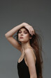 © SHOTPRIME STUDIO - Elegant woman posing with long hair and black top, displaying confidence and grace in a minimalistic studio setting.