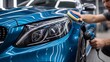 © nur khayati w - Man polishing blue car headlight in a detailing shop, background with blurred interior. Automotive service