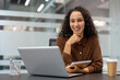© Liubomir - Confident woman with a notepad and laptop enjoying her work in a stylish office. The setting is informal yet professional, suggesting productivity, creativity, and modern workplace design.