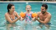 © Iurii - Family enjoying a sunny day at the pool with their young child splashing water