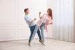 © New Africa - Happy couple dancing together near white wall at home