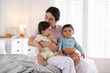 © New Africa - Mother with her cute little twin babies on bed indoors