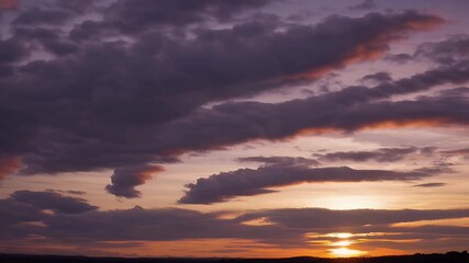 Wall Mural - Fast motion 4K time lapse capturing a warm summer sunset sky filled with soft white clouds drifting rapidly above a golden yellow horizon delivering an uplifting and peaceful atmosphere for nature