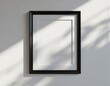 © Pete - Rectangular black picture frame hangs on clean white wall. Empty blank matting inside frame is ready for custom artwork or photo placement. Natural light casts shadows across the surface.