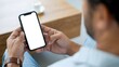 © Arnab Dey - Mockup, woman's hands holding mobile phone with blank screen in coffee shop. Woman using smartphone, looking at the screen, over shoulder view