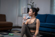 © Apichat - Asian woman drinking water after exercising at home