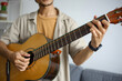 © Gatot - Young Man's Hands Playing Chords On Acoustic Guitar