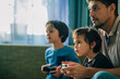 © Westend61 - Father and children playing video game together at home
