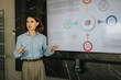© qunica.com - A professional woman leads a presentation with a digital display in a modern office setting, engaging a diverse business team in discussion and collaboration.
