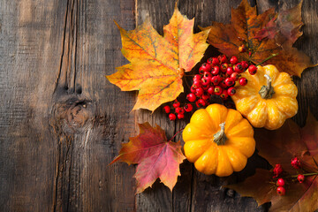 Poster - Top view of Autumn maple leaves with Pumpkin and red berries on old wooden background. Thanksgiving day concept.