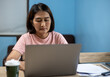© Kanokwan - Woman sitting on chair working from home while typing with laptop on desk, learning online upskill for business, vacation life lifestyles concept