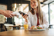 © standret - Laptop, salad and orange juice. Woman is paying for meal by wireless payment in the cafe restaurant