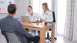 © chekart - A surgeon and orthopedic surgeon talks to a patient in the hospital's medical office. The man came to consult a doctor. Two women in white coats
