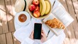 © Kaifiya - A tranquil flat lay of a morning routine featuring a smartphone, a healthy breakfast, and a book outdoors