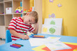 © WavebreakMediaMicro - Boy drawing with colored pencils at blue table in children's activity room featuring painted canvas