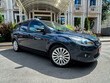 © DSMT - A stylish blue hatchback is elegantly parked right in front of a luxurious and grand building, surrounded by beautifully maintained landscaping that really enhances the vibrant urban environment