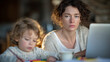 © Maksym - Frustrated mother typing hurriedly on a laptop at a dining table strewn with documents and a half-empty coffee cup. Her child sits close by, absorbed in colorful drawings, unaware