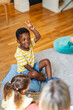 © lordn - Smiling boy raising his hand during a preschool music activity, showing engagement in a diverse and inclusive classroom