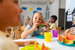 © lordn - Preschool children enjoying fresh watermelon slices during snack time in bright and cheerful classroom