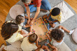 © lordn - Preschool children and teachers sitting together, threading colorful beads to create necklaces, developing fine motor skills, creativity, and hand-eye coordination in a fun classroom activity