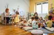 © lordn - Preschool teacher with diverse children playing and interacting on the floor in a bright classroom, encouraging teamwork, social skills, and joyful learning through play