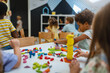 © lordn - Preschool children playing with colorful building blocks and shapes at a classroom table, developing creativity and motor skills