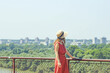 © tanyatorgonskaya - Panoramic Belgrade view from Kalemegdan fortress, Serbia: a woman in a straw hat and red dress admires the summer city skyline over the Danube River. Harmony between city life and green landscapes.