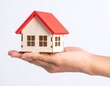 © Uang - Hand holding a small wooden house model