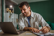 © Miljan Živković - Freelancer smiling and working from home office using laptop