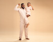 © The Yudel Media - An African father and son in matching beige outfits flex their arms proudly in a warm studio setting, capturing strength, joy, and the powerful bond of love and connection between generations.