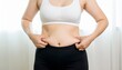 © Senja - Woman in Sports Bra and Leggings Pinching Excess Belly Fat